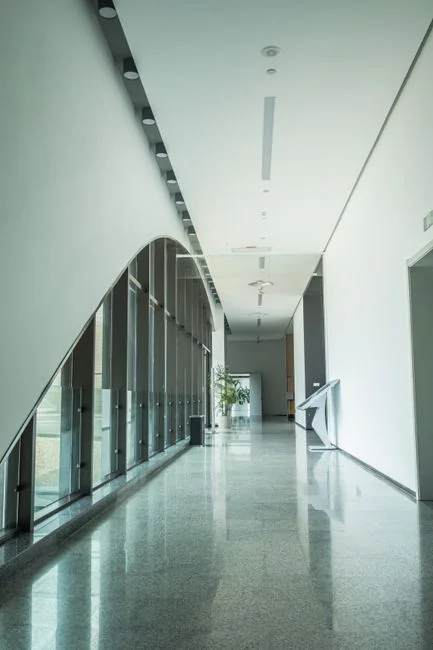 A spacious, modern office interior featuring glass partitions, elegant furnishings, and colorful wall art.